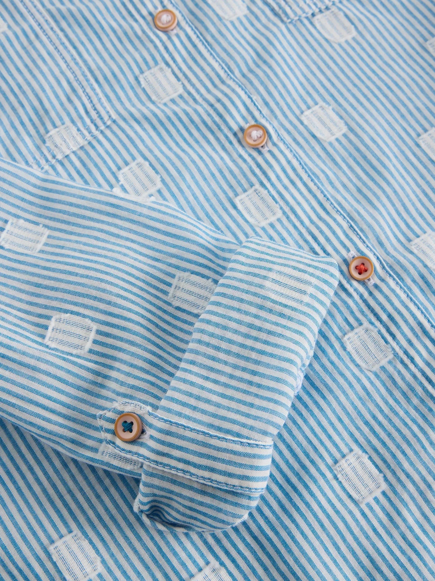 Update your button-up style with Sophie Organic Cotton Shirt - Light Blue Stripes - a playful twist on the traditional white shirt. With a combination of blue stripes and white squares, it's a statement-making piece that will elevate your wardrobe instantly. Trust us, you won't be able to pass up this charming print!