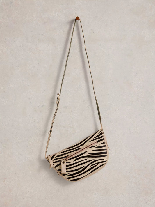 the Caro Crossbody Bag from White Stuff. Its crescent shape is updated for a modern twist. You'll be delighted by the multitude of zippered pockets and an adjustable strap for the perfect fit. Plus, who can resist the abstract zebra print in luxurious calf hair?