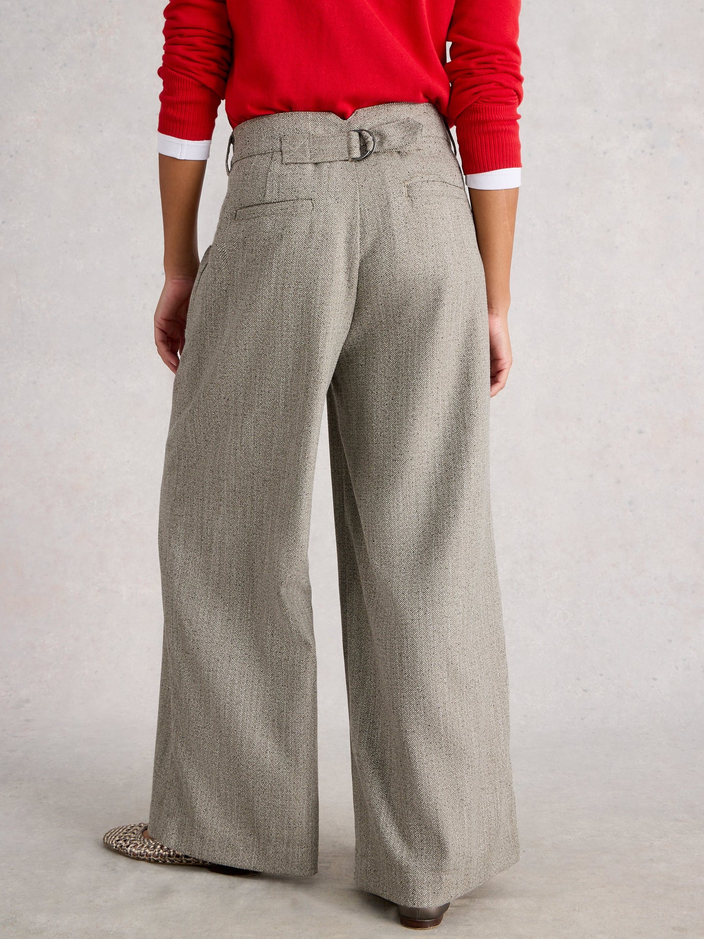 Person wearing a red sweater and gray wide-leg pants on a plain background