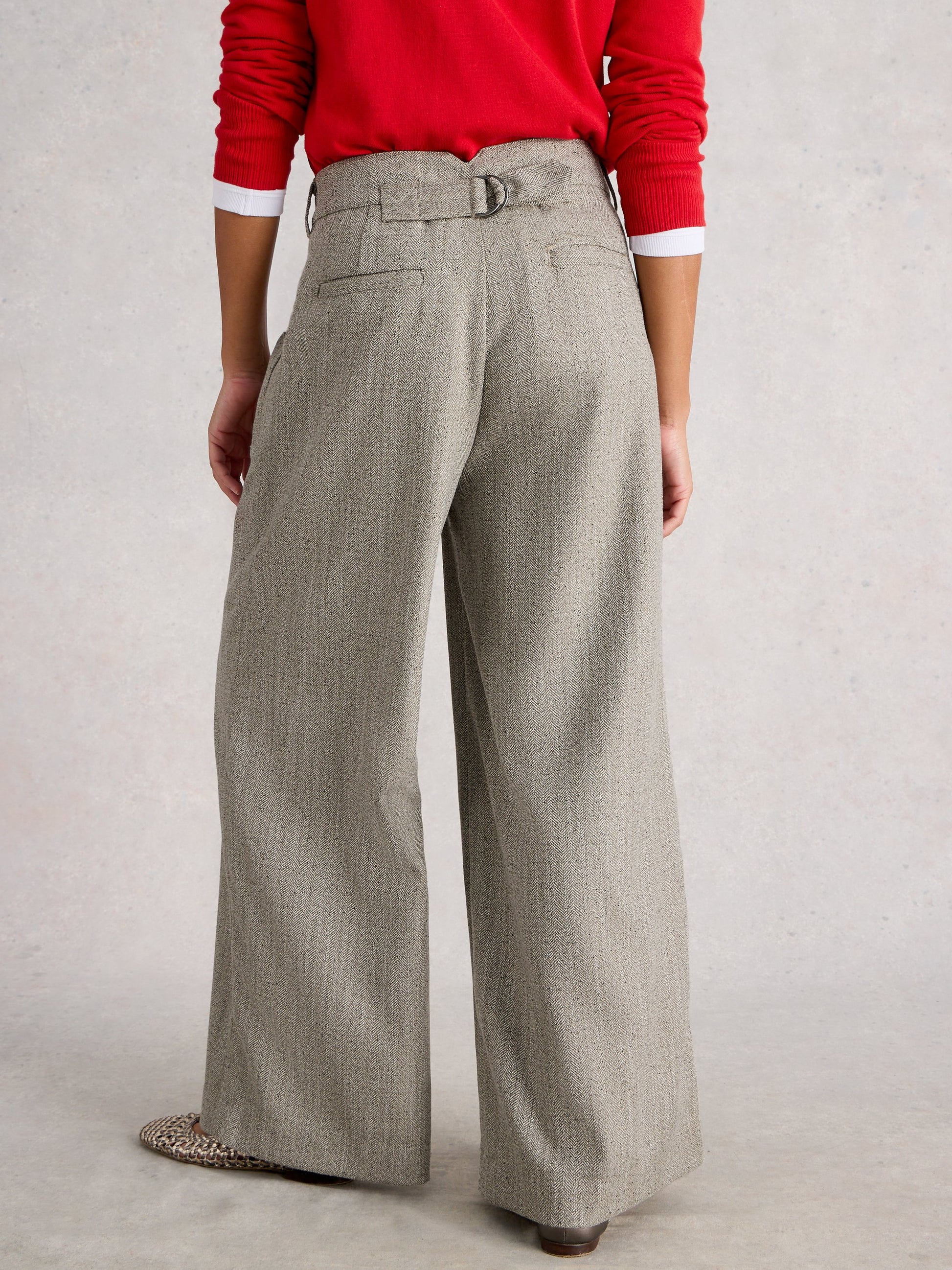 Person wearing a red sweater and gray wide-leg pants on a plain background
