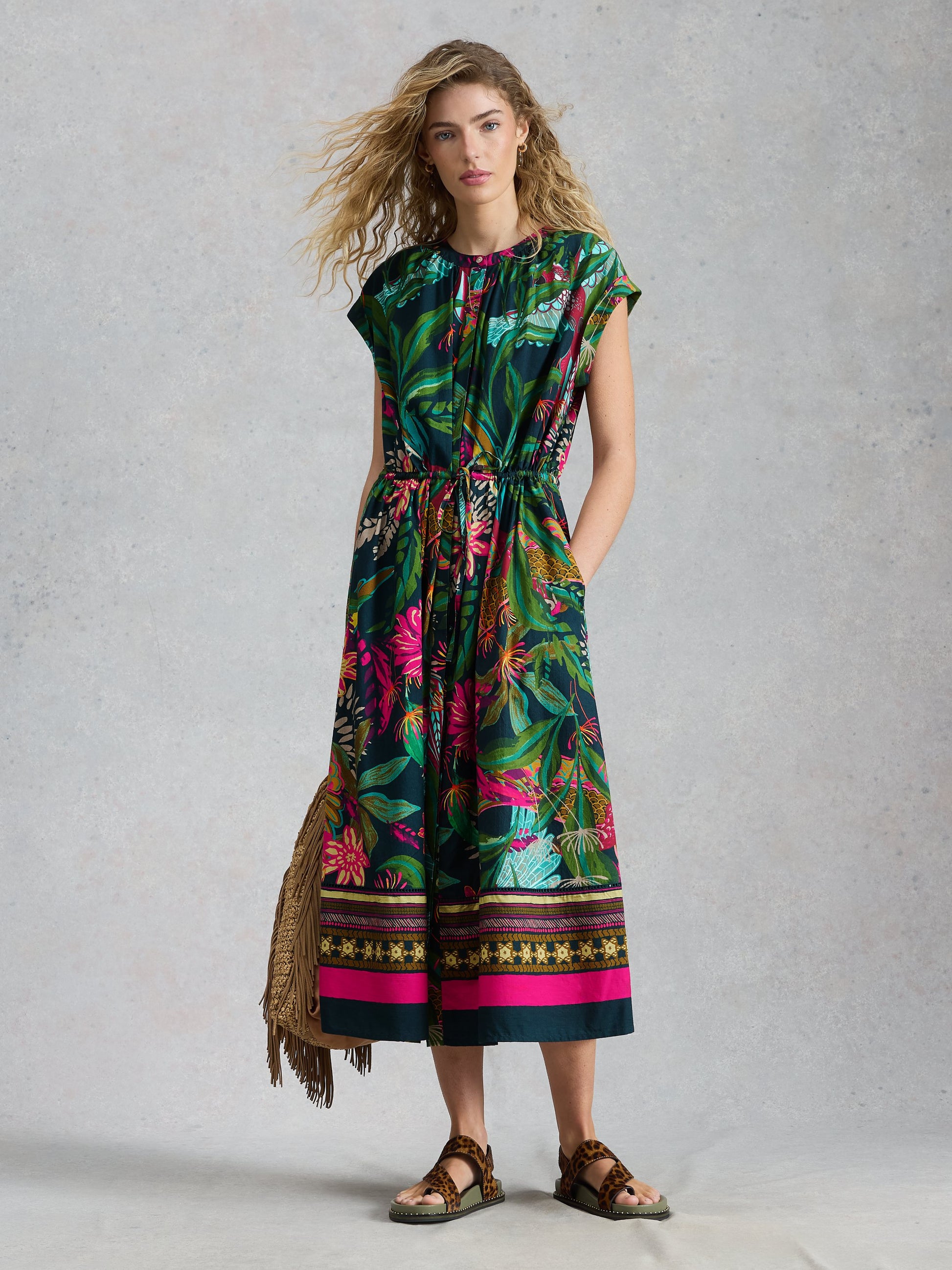 Woman wearing a colorful floral dress with a patterned border against a gray background