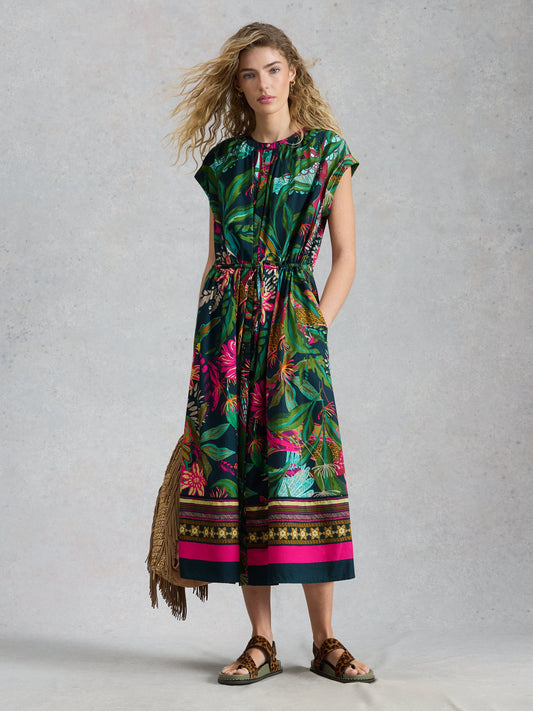 Woman wearing a colorful floral dress with a patterned border against a gray background