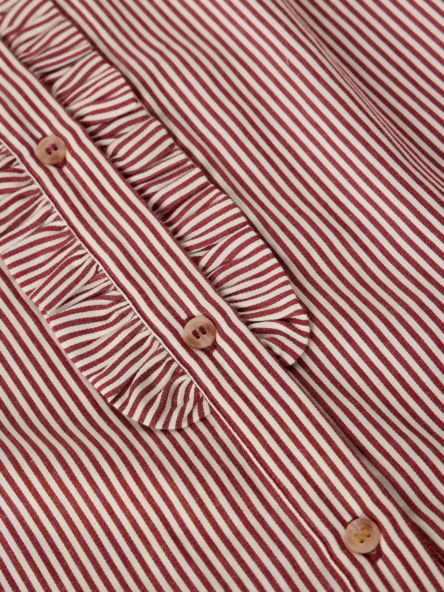Close-up of a red and white striped blouse with a ruffled collar and decorative buttons.