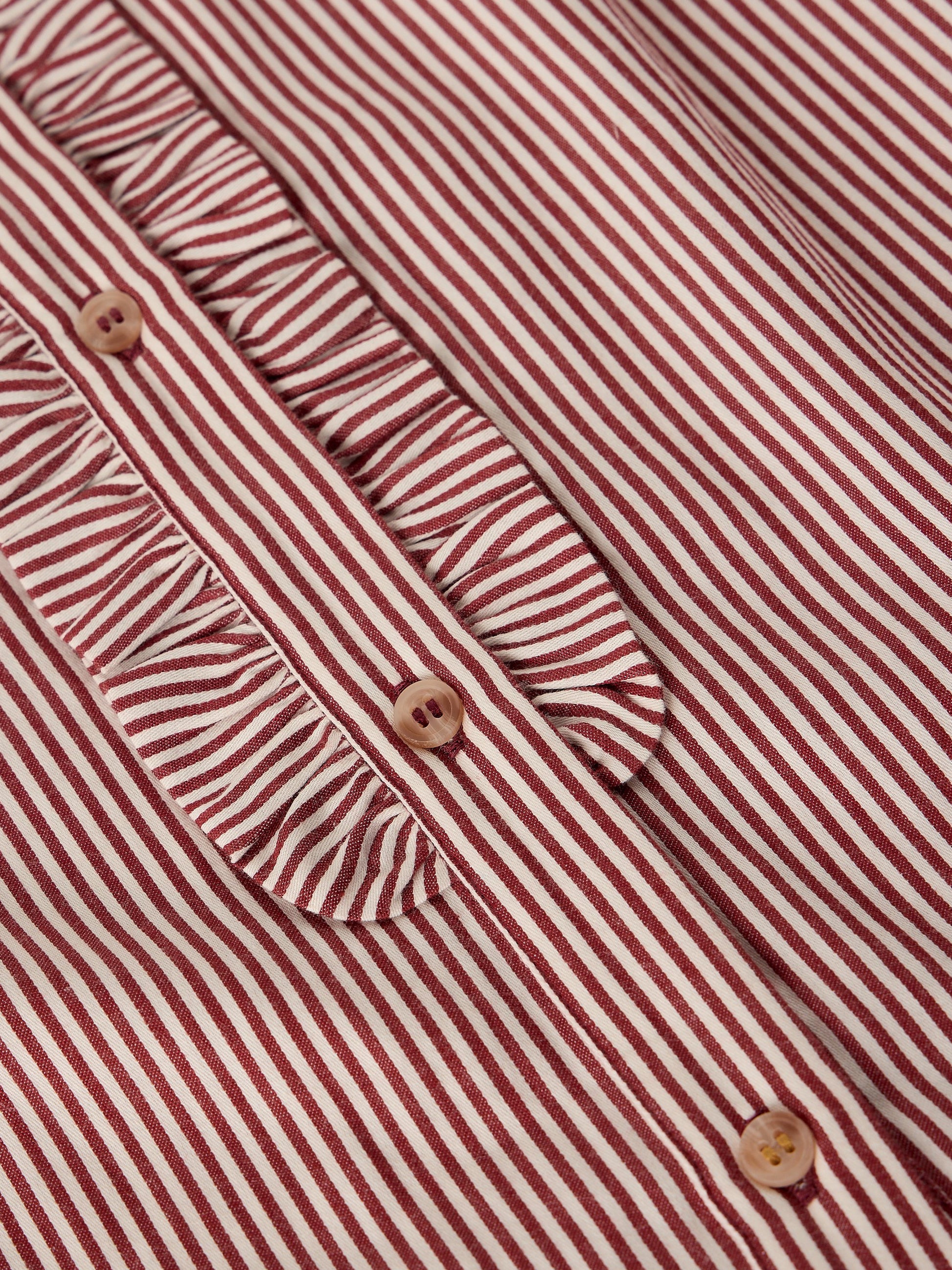 Close-up of a red and white striped blouse with a ruffled collar and decorative buttons.