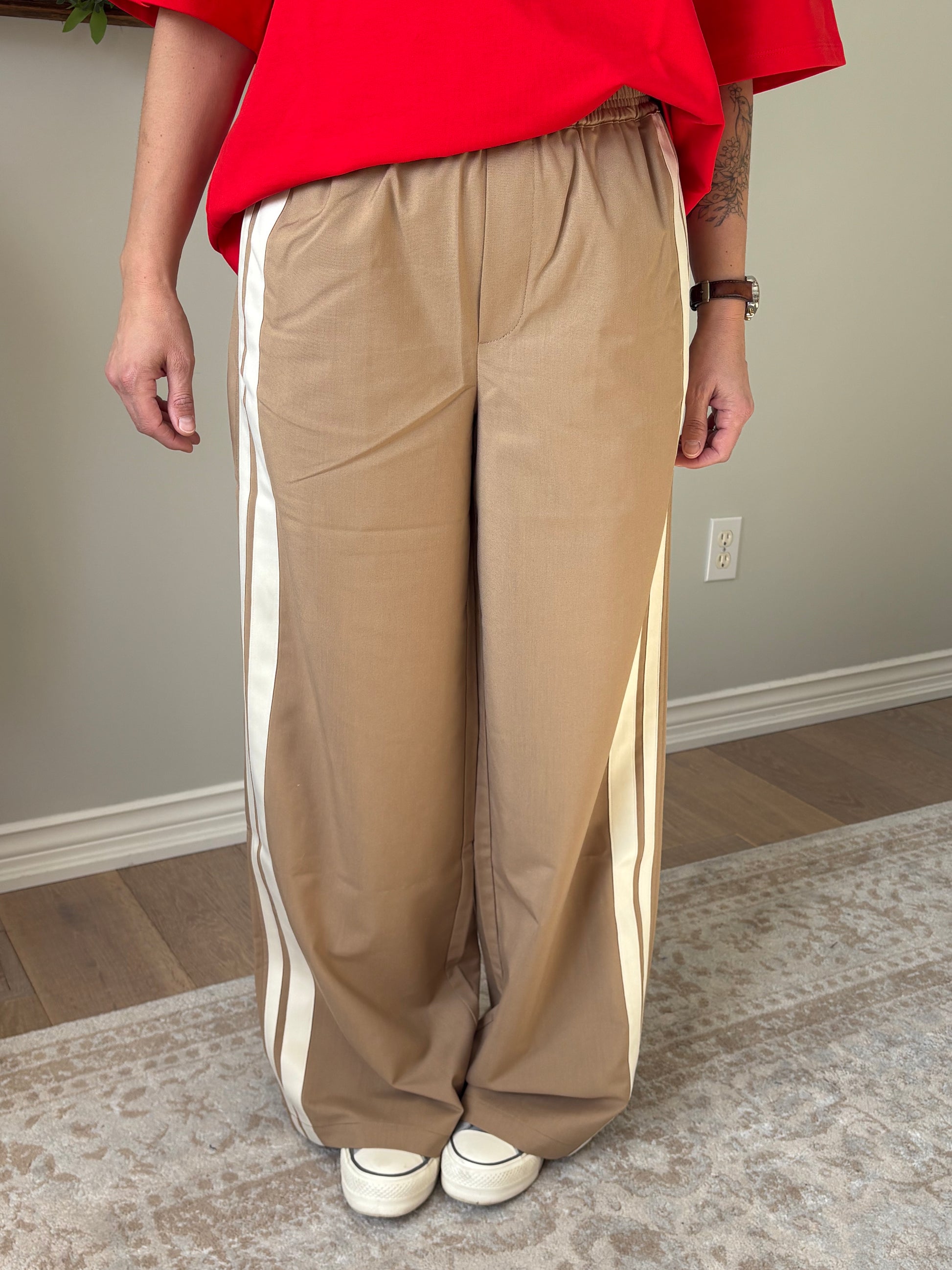 Person holding a folded beige blanket in a room with a neutral color scheme.