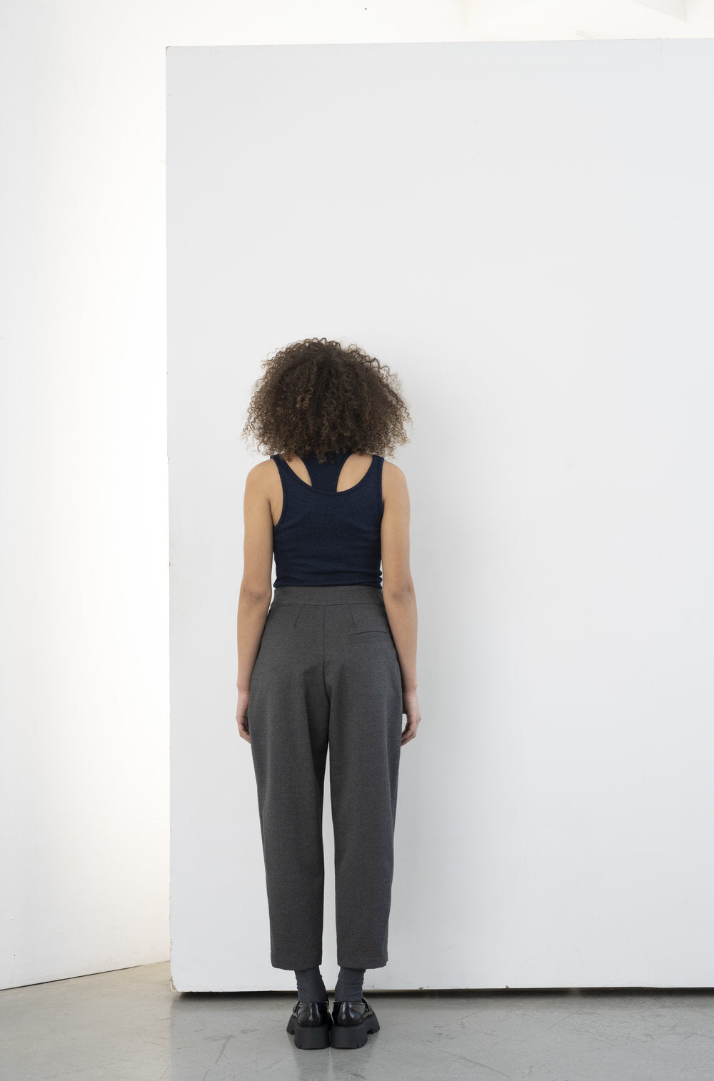 The Olden Pant in charcoal by BODYBAG by Jude is a high-waisted, carrot-style pant with two pleats on each side at the front, an invisible zipper on the side, and one back pocket. lemon cyprus boutique