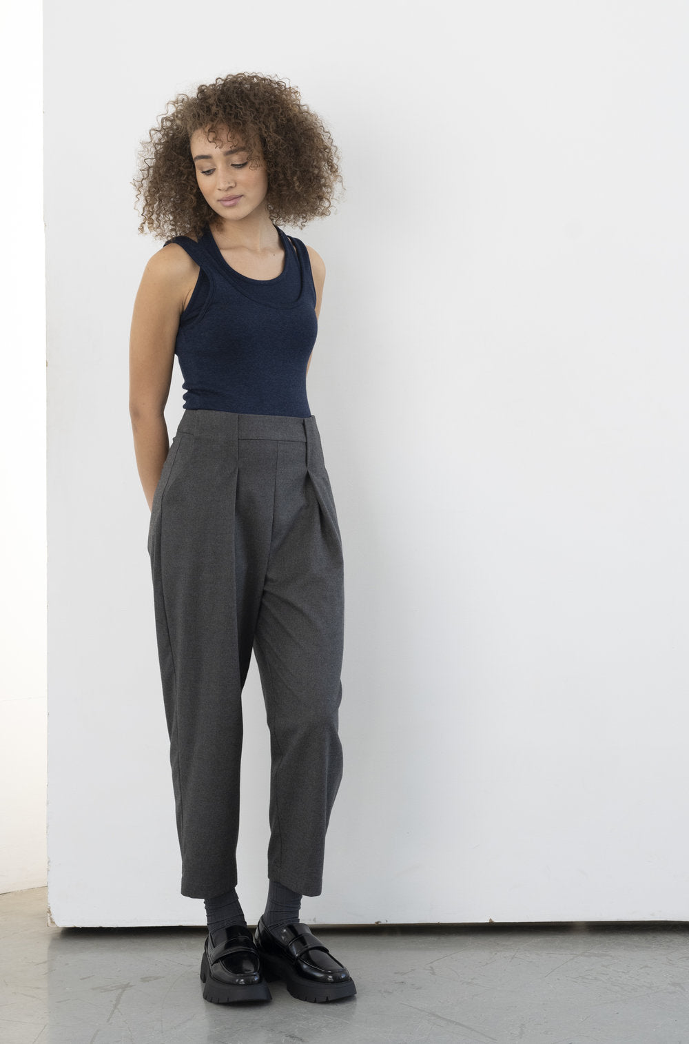 The Olden Pant in charcoal by BODYBAG by Jude is a high-waisted, carrot-style pant with two pleats on each side at the front, an invisible zipper on the side, and one back pocket. lemon cyprus boutique
