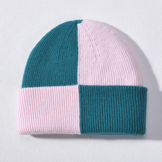 Teal and blush pink checkerboard colour block cashmere-blend beanie, laid flat on a light background.