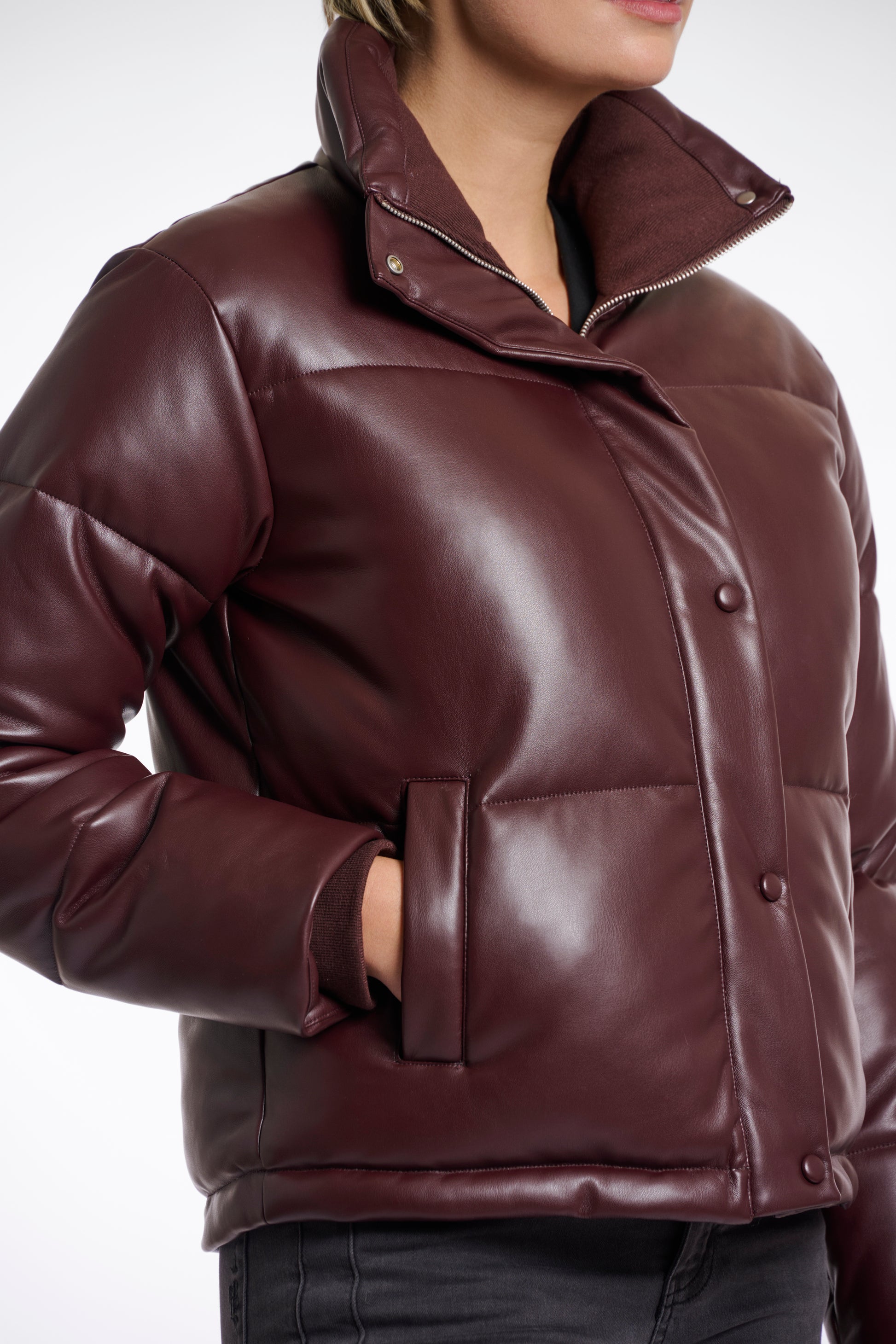 Brown leather jacket worn by a person on a white background