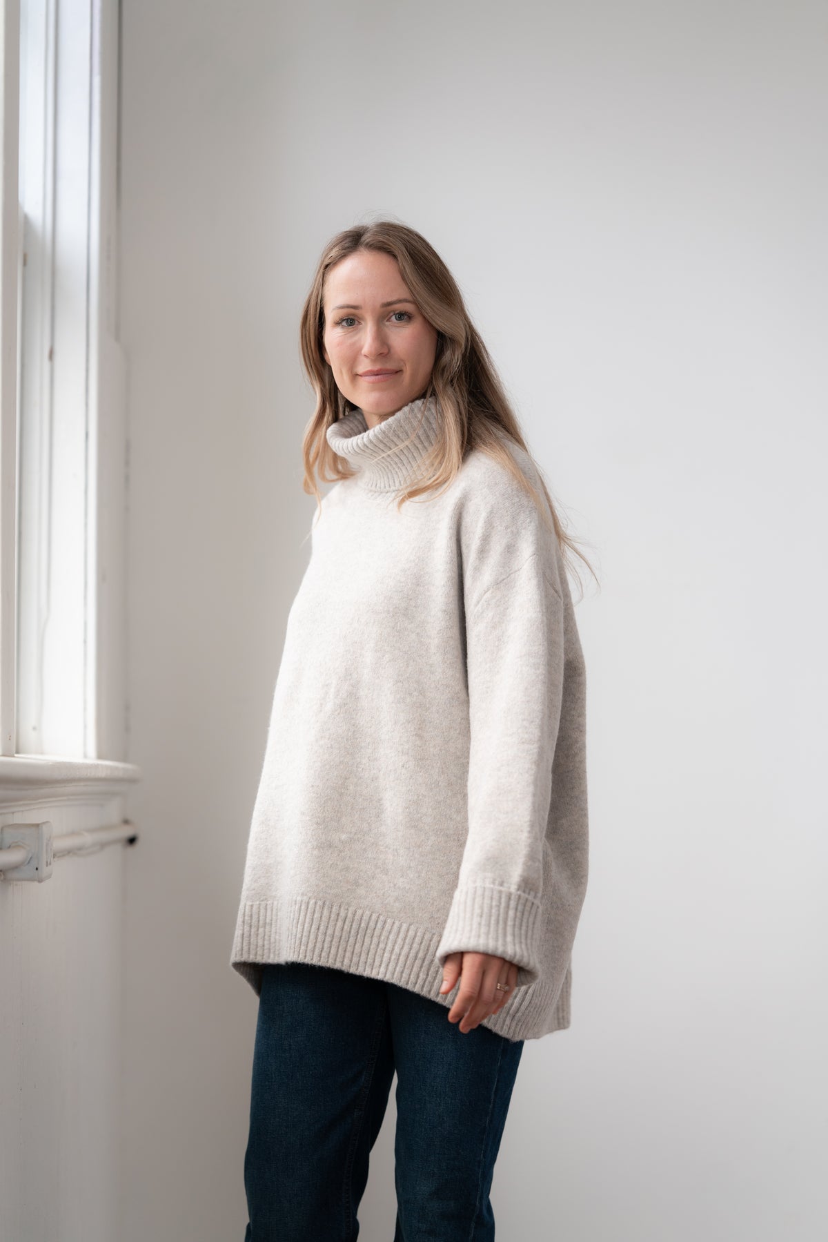 Woman wearing the Echoverde Dog Walker fawn chunky cowl neck sweater with dark jeans