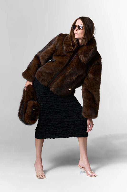Woman wearing a brown fur coat and black skirt on a white background