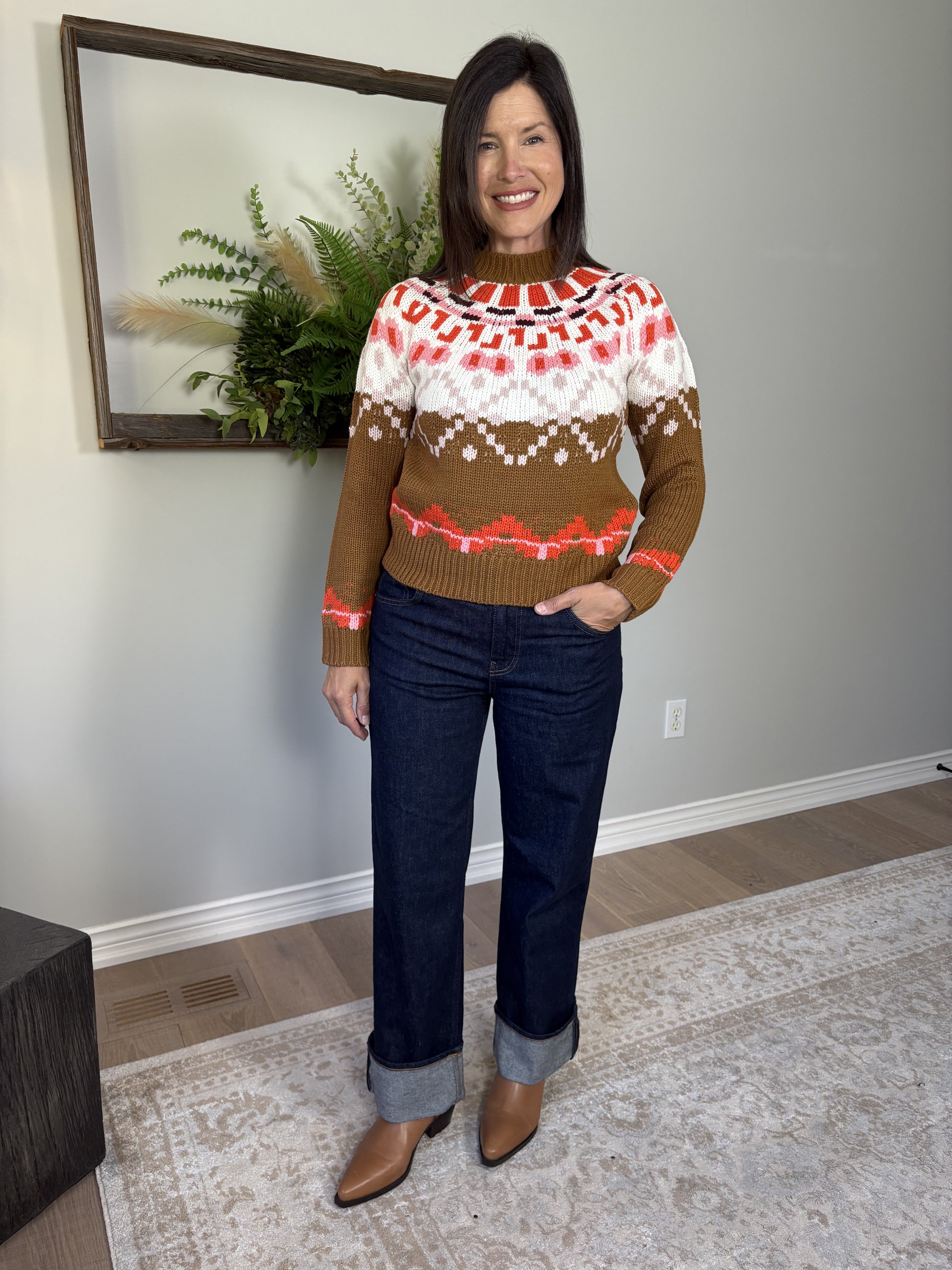 Woman wearing a patterned sweater and jeans indoors.
