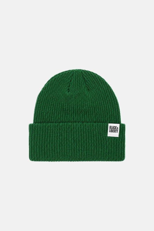 A dark green ribbed knit beanie hat with a folded cuff, featuring a small white rectangular brand patch on the side that reads 'BLACK CREAM'. The product is photographed against a clean, light gray studio background.