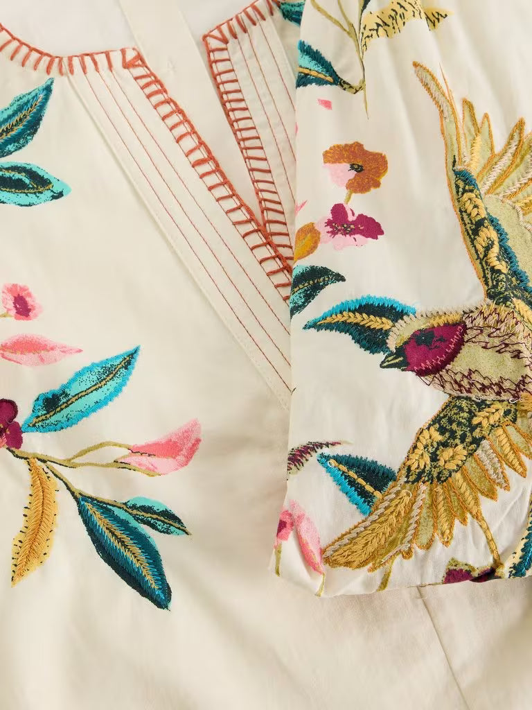 Embroidered fabric with colorful birds and floral patterns on a beige background