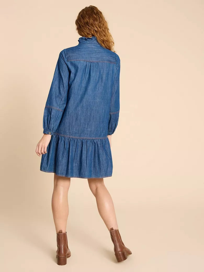  the Maisie Denim Dress by White Stuff – a stylish and comfortable piece perfect for day-to-night wear. Made from 100% cotton, this dress features a high neck, long sleeves, a relaxed fit, and a feminine touch with a charming ruffle detail. With a knee-length cut, it effortlessly blends comfort and style. Its easy-care, machine-washable design makes it practical and fashionable, embracing the denim trend with a delightful feminine flair.