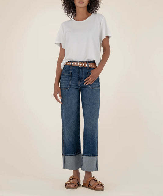 Person wearing a white t-shirt, blue jeans, and brown sandals on a beige background