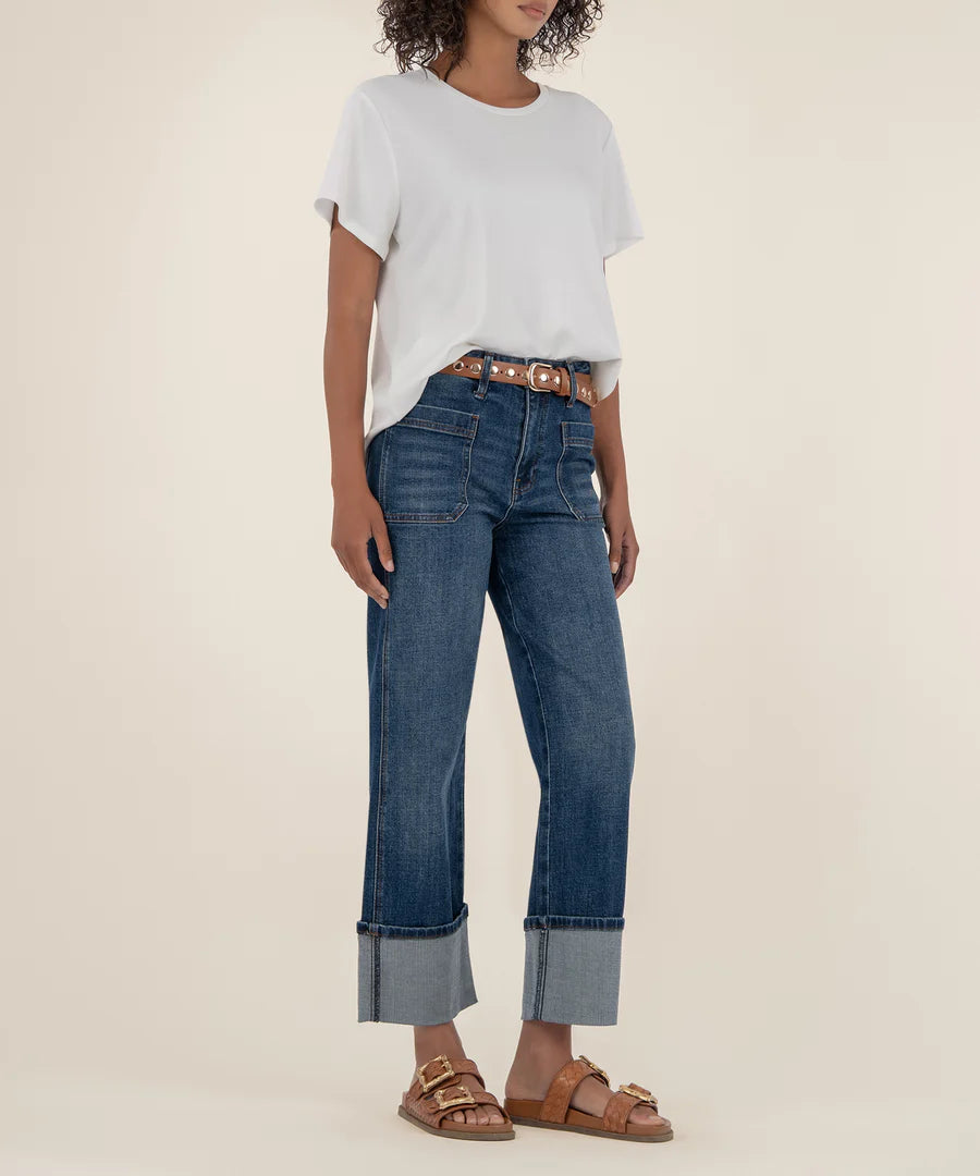Person wearing a light gray top and blue jeans on a beige background