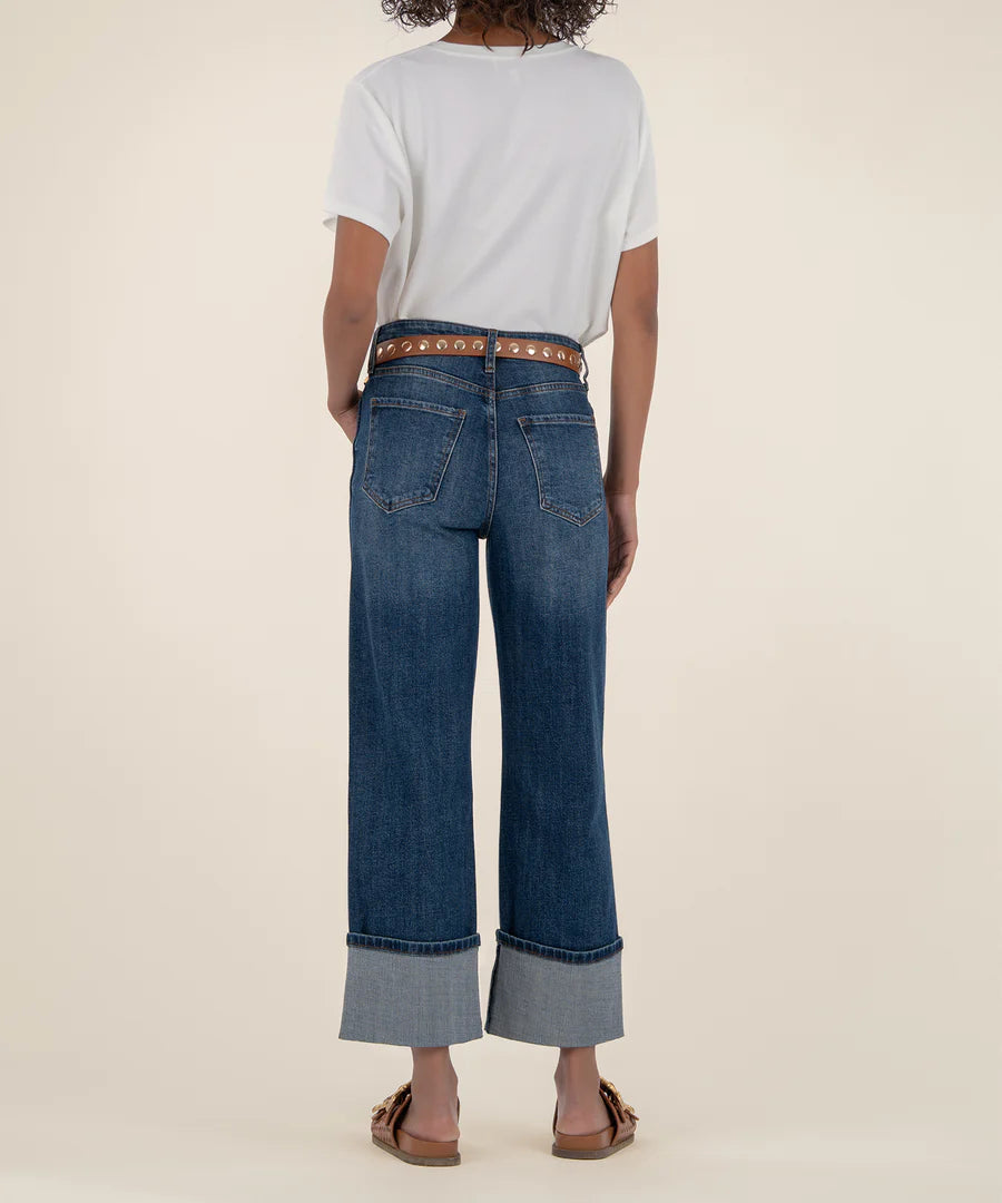 Person wearing blue jeans and a white shirt on a beige background