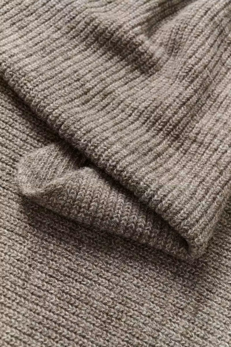 Close-up of a ribbed knit fabric in a warm taupe-gray color, showing the texture and folds of the material.