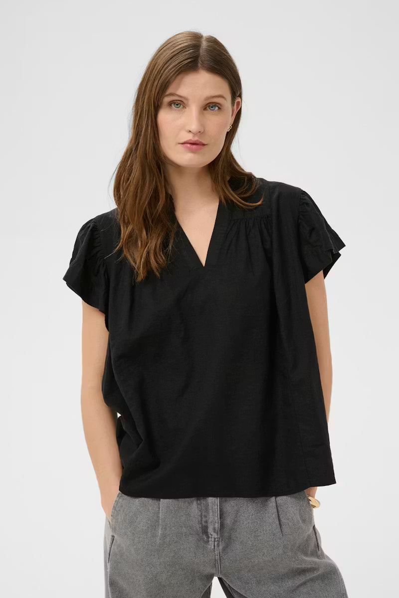 Woman wearing a black top and gray pants on a white background