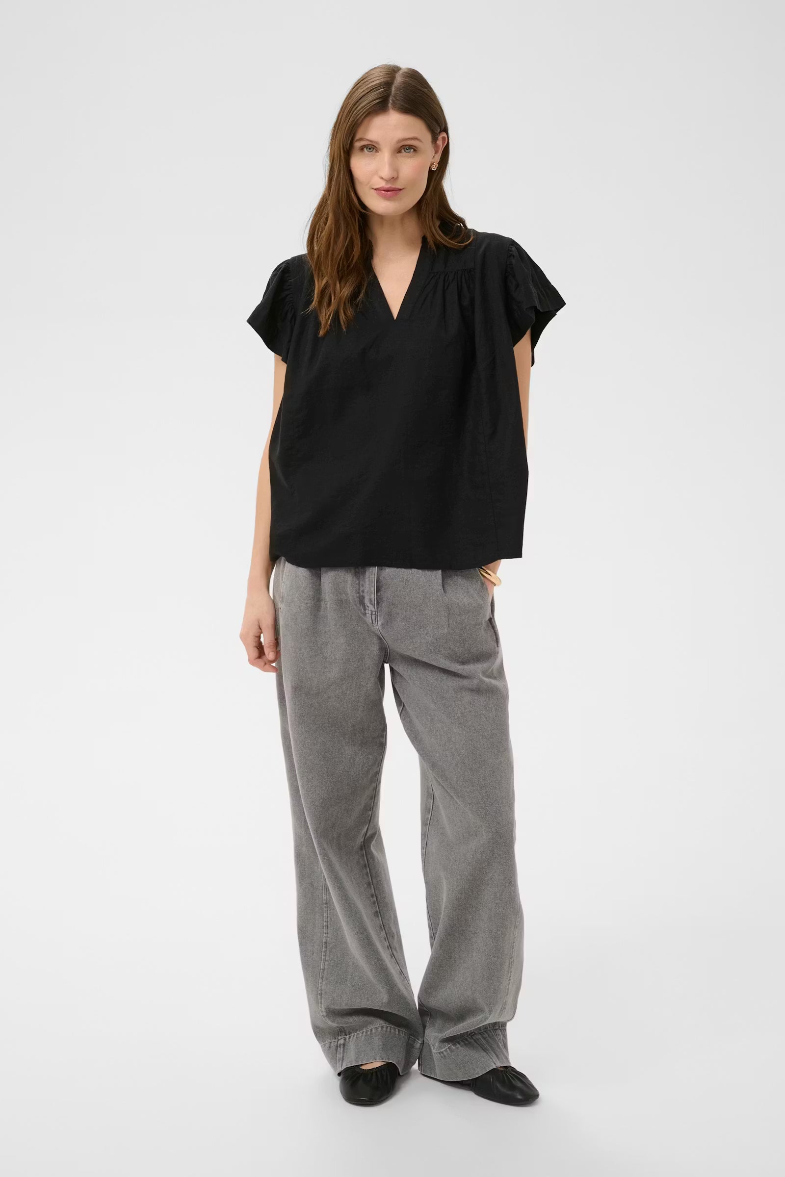 Woman wearing a black top and gray pants on a white background