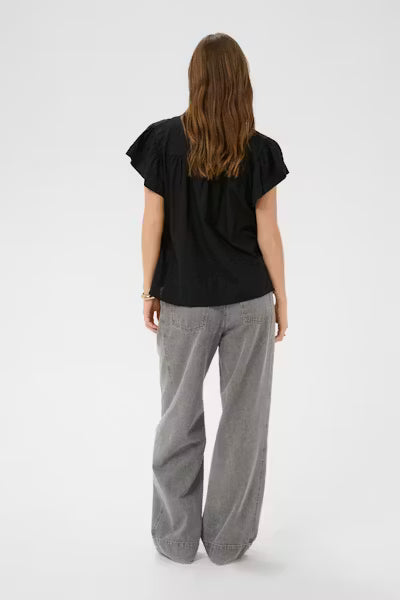 Person wearing a black top and gray pants on a white background