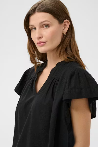Woman wearing a black blouse with ruffled sleeves on a white background