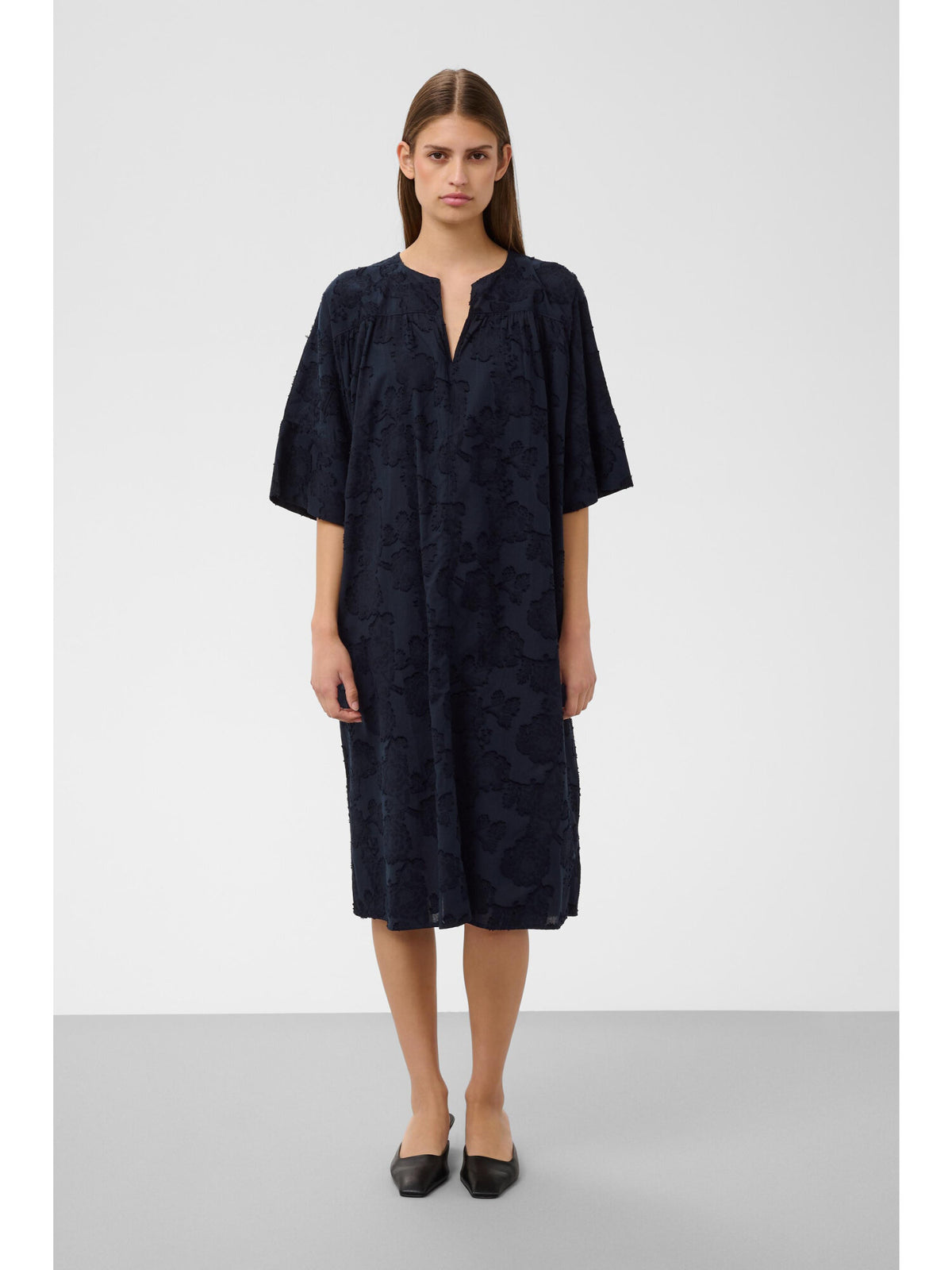 Woman wearing dark navy tone-on-tone jacquard midi dress by Soaked in Luxury with black mule flats
