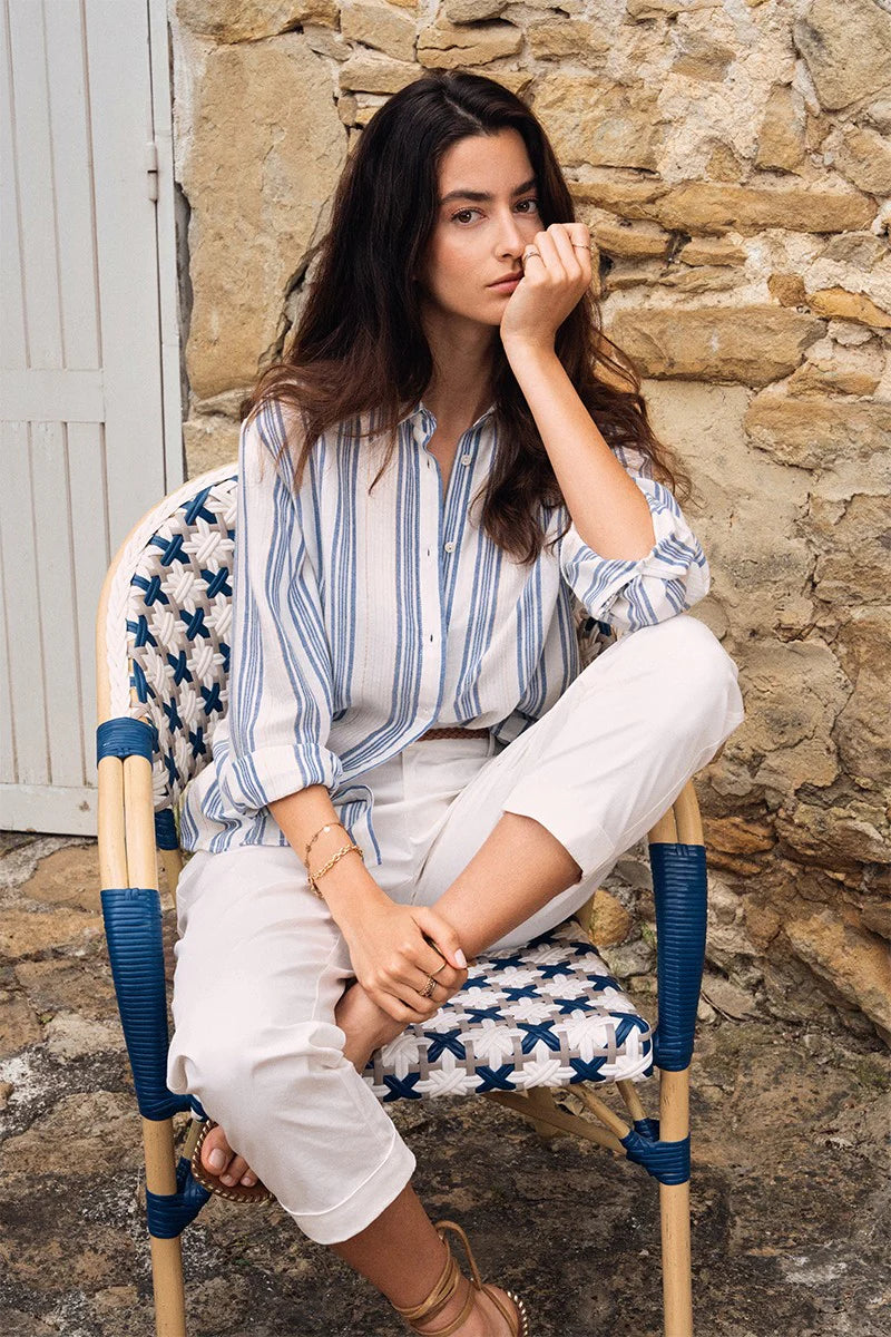 Woman sitting on a chair against a stone wall