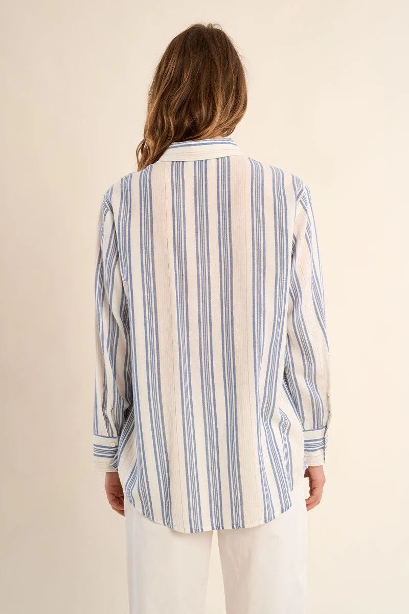 Woman wearing a blue and white striped shirt against a beige background