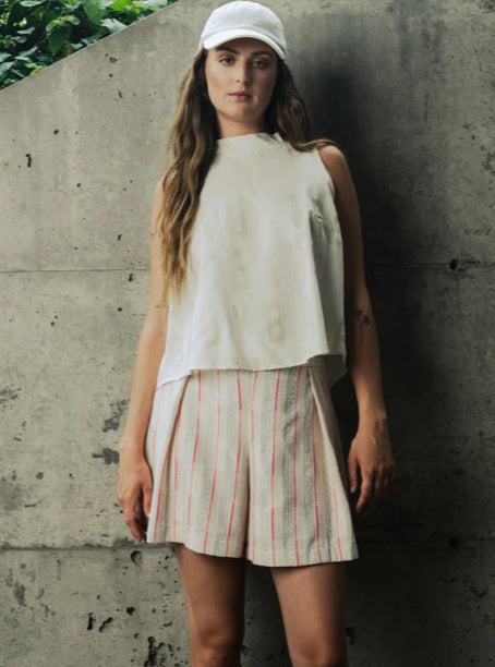 Introducing the Sao Paulo Shorts by BODYBAG By Jude, a chic addition to your summer wardrobe. These high-waisted shorts feature a flattering flared cut with front pleats and back darts for a stylish fit. They're designed with invisible zip and side pockets for convenience, along with a welt pocket at the back. Made from a beautiful fabric of creams with thread accents of bold right pink, custom woven in France, these shorts are both elegant and versatile, perfect for any occasion.