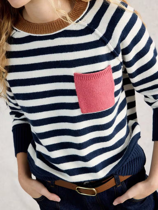 Person wearing a navy and white striped sweater with a pink pocket on a neutral background
