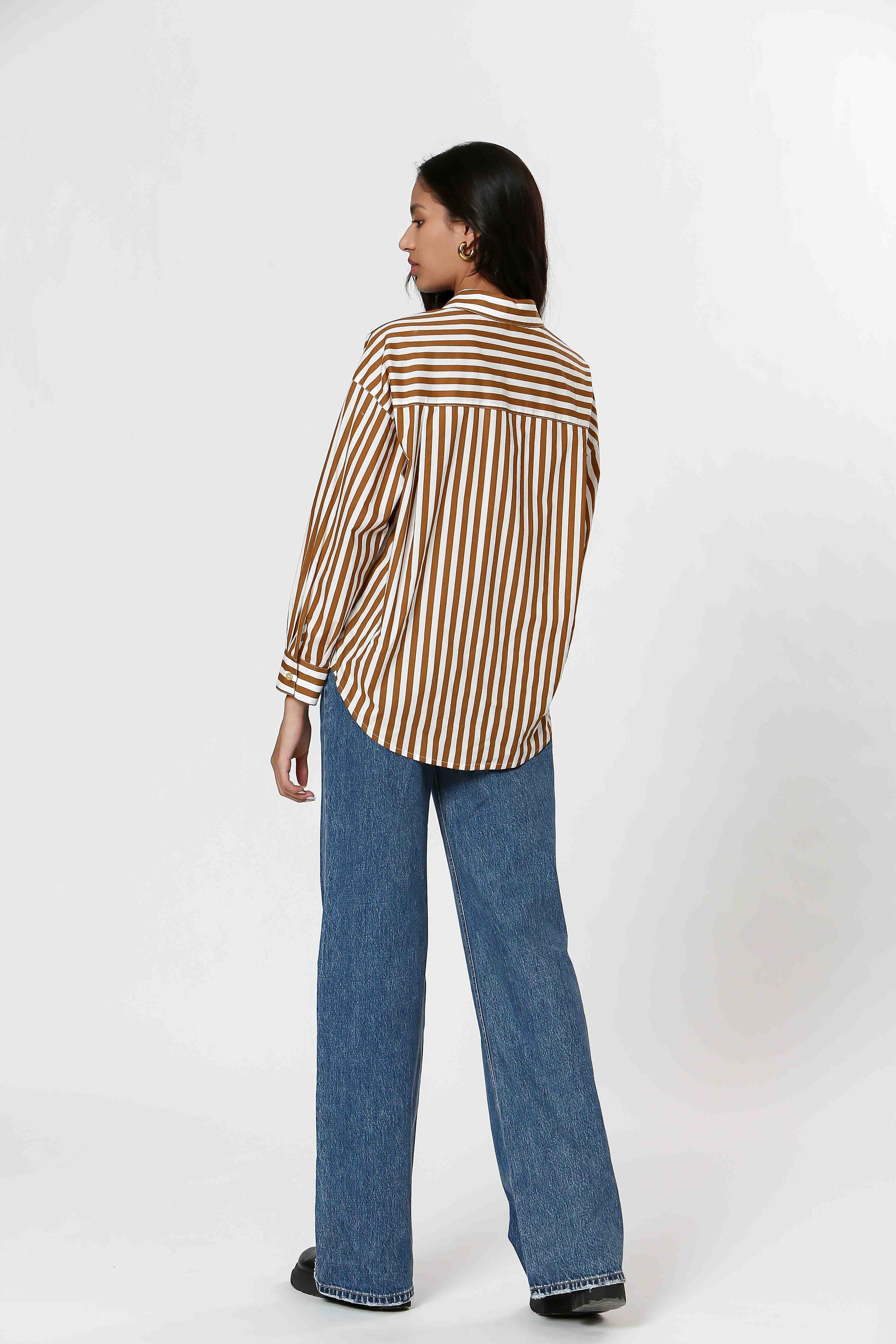 This Striped Blouse by The Korner adds a touch of fun to your wardrobe with its white and camel stripes. Versatile enough for layering or wearing on its own, this button-down blouse will make you stand out in style.