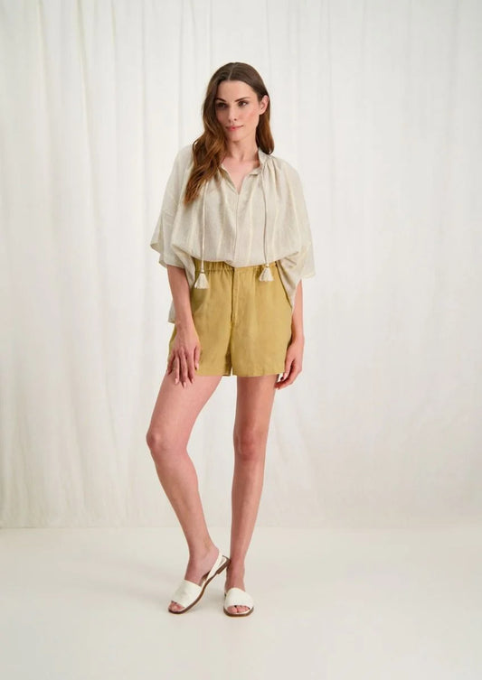 Introducing the Avril Blouse in Antique White by Circle of Trust. Made from soft 100% cotton, it's comfy and breathable for everyday wear. The loose fit and vertical stripe pattern give it a relaxed yet stylish vibe. With a V-neck and delicate strings, it's effortlessly charming. Plus, it has drop shoulders and wide sleeves for a comfy fit. Finished with tassel ties and subtle ochre accents, it's a versatile piece for any occasion. Pair it with denim shorts or a skirt for a casual look. 