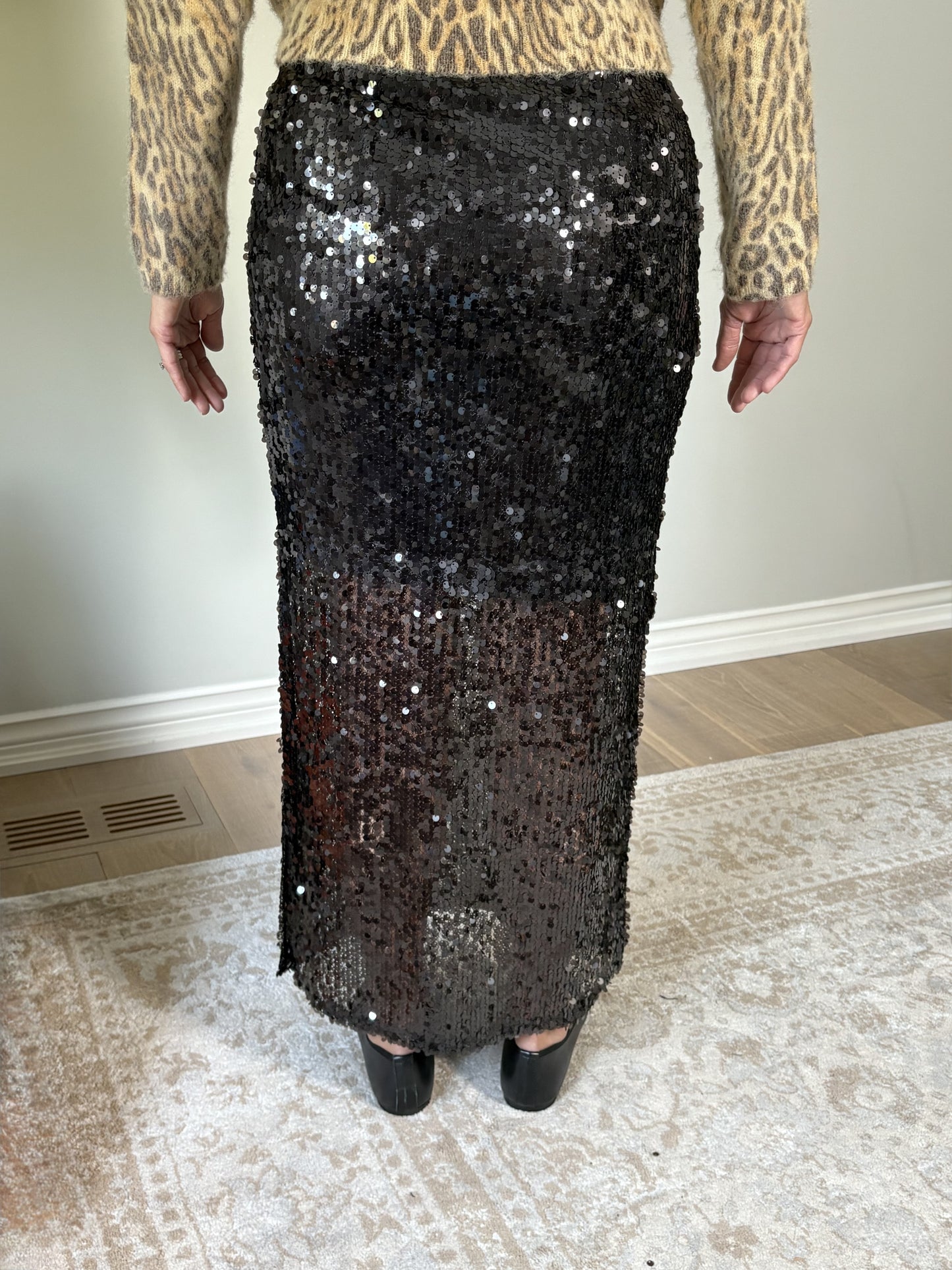 Person wearing a brown sequin skirt and leopard print top indoors.