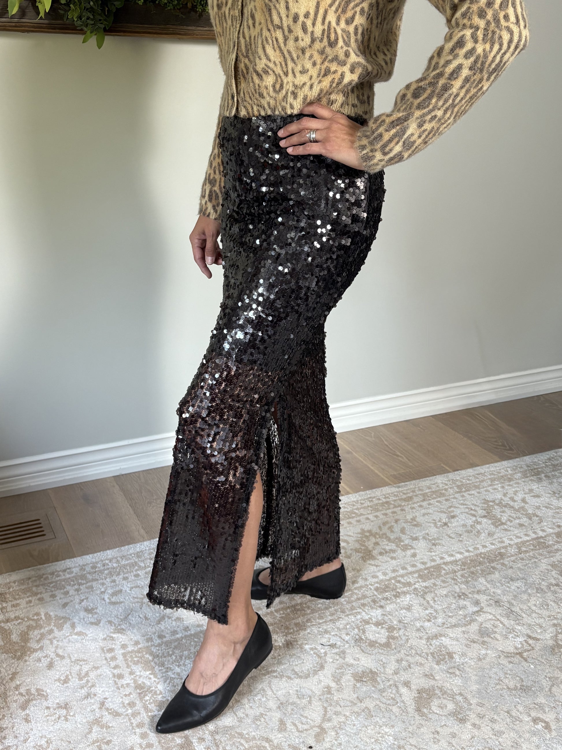 Person wearing a leopard print top and brown sequin skirt indoors.