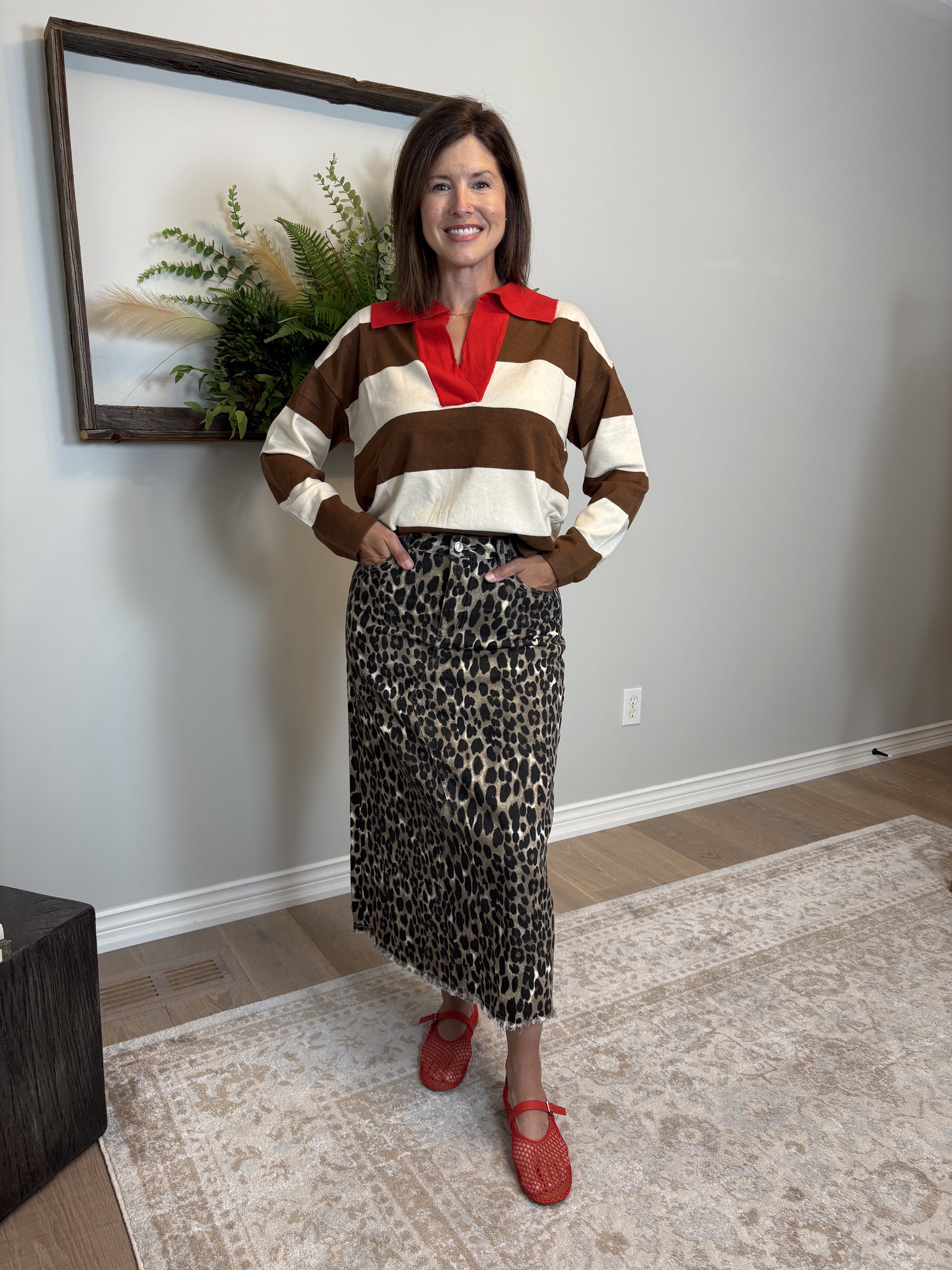 Woman wearing a striped sweater and leopard print skirt indoors.
