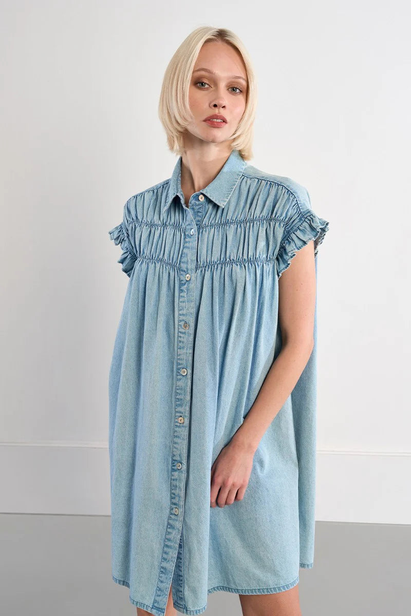 Woman wearing a light blue denim dress against a plain background