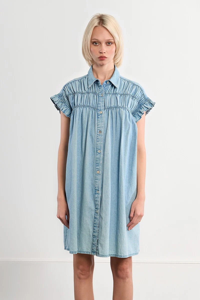 Woman wearing a light blue denim dress against a white background