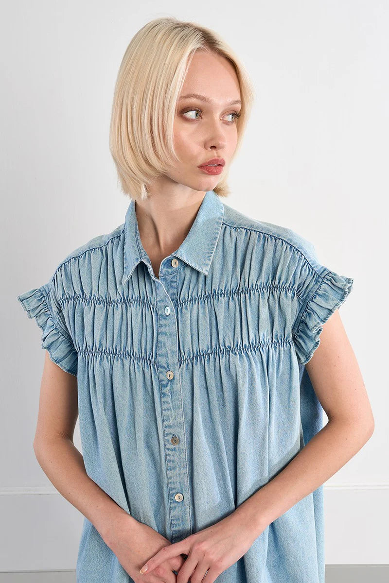 Woman wearing a light blue denim dress against a plain background