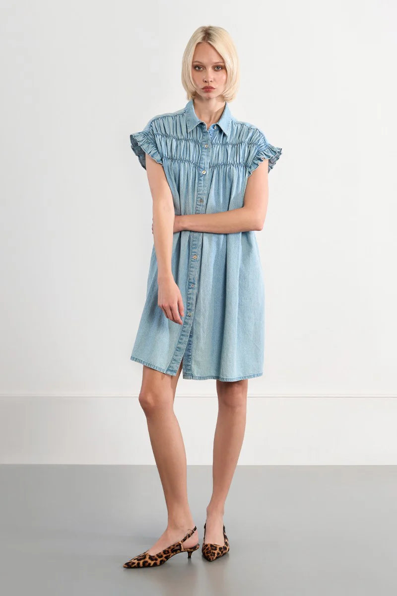 Woman wearing a light blue denim dress against a white background