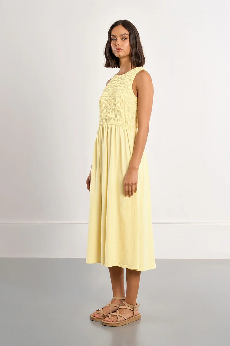 Woman wearing a yellow dress standing against a plain background
