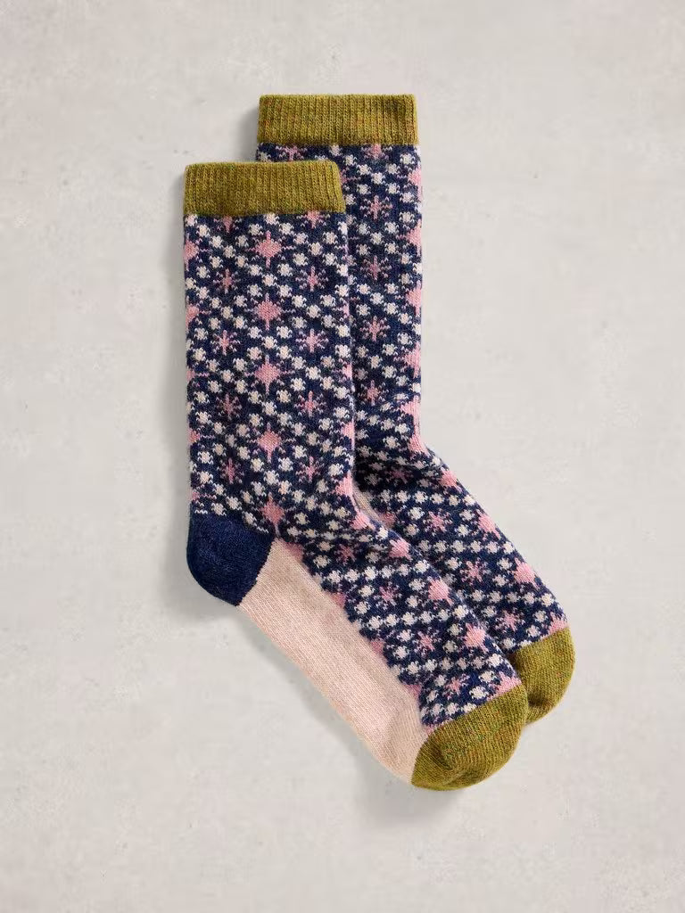 Pair of patterned socks with green cuffs and toes on a light gray background