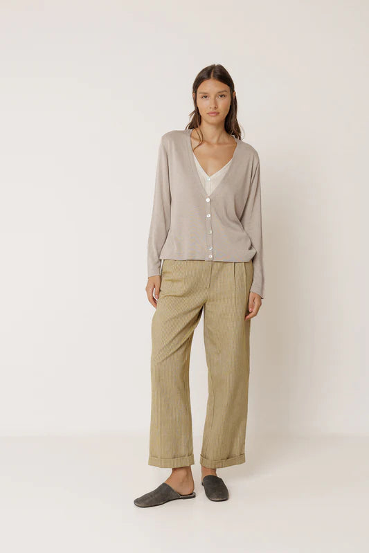 Woman wearing a beige cardigan and pants on a white background