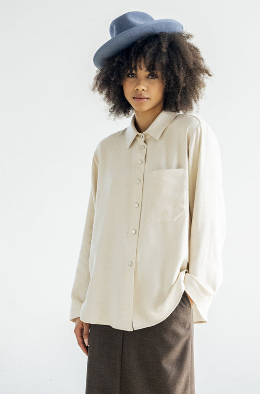 Effortlessly stylish and always on trend. Featuring a twist on the classic button-down style, the Douglas Top in a beautiful vanilla colour is a versatile addition to your wardrobe. Complete with our signature square matte metal buttons, one front pocket and a pleated back. This shirt is a must-have for any fashion-forward individual.