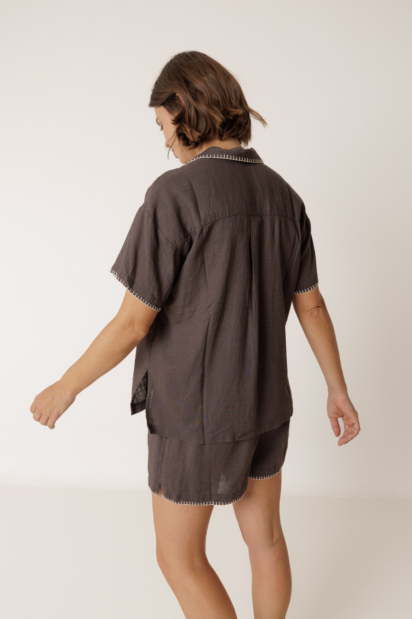 Woman wearing a dark brown outfit with a plain background