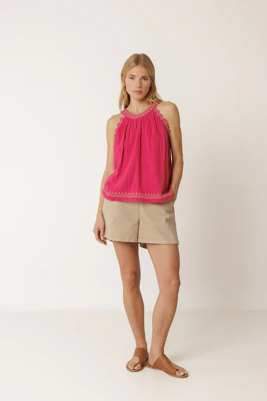 Woman wearing a pink top and beige shorts on a white background