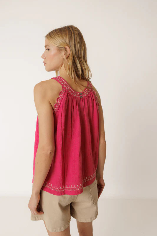 Woman wearing a pink sleeveless top with lace details on a white background