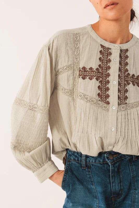 Light-colored blouse with intricate embroidery on a plain background