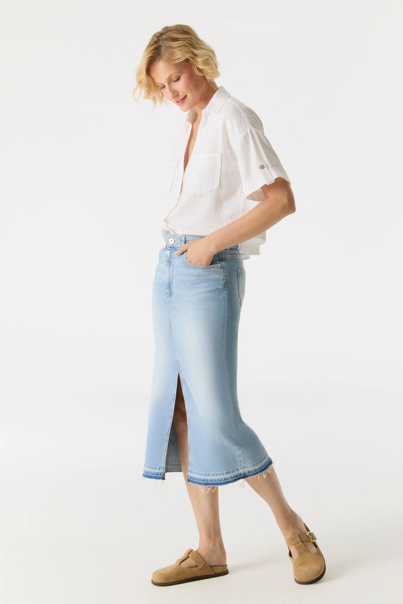 Woman wearing a white blouse and light blue denim skirt on a white background
